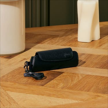 Estojo individual em couro Saffiano Jet Black para Ploom AURA sobre uma mesa  