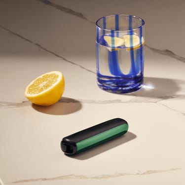 Acessório painel frontal Amazon Green para Ploom AURA aplicado ao dispositivo sobre uma mesa.