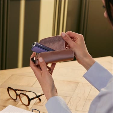 Utilizador a retirar um dispositivo Ploom AURA do Estojo Individual em couro sintético Rose Gold